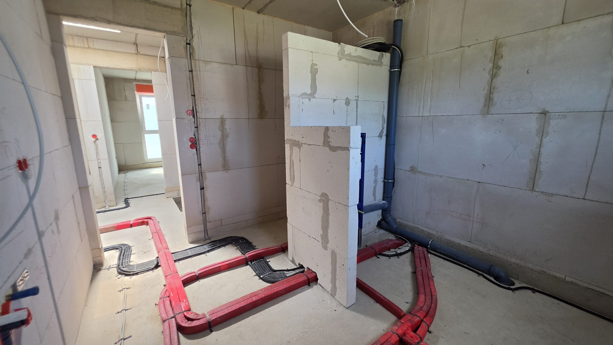 Badezimmer mit Fußbodenheizung — rote Heizrohre und WC-Installation, Mai 2026